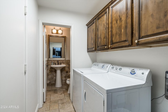 clothes washing area featuring cabinets, washer and clothes dryer, and sink