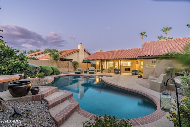 pool at dusk with an outdoor living space and a patio area