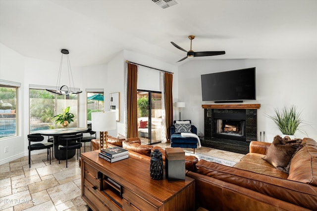 living room with ceiling fan with notable chandelier, lofted ceiling, and a fireplace