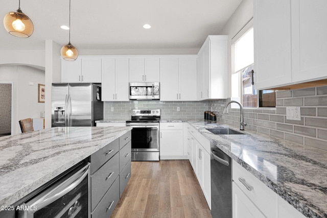 kitchen featuring sink, white cabinets, beverage cooler, hanging light fixtures, and stainless steel appliances