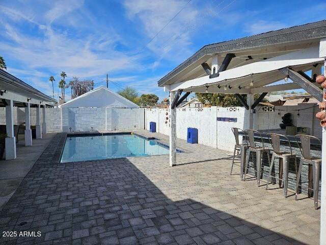 view of swimming pool featuring a patio and an outdoor bar