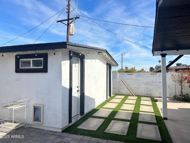 view of side of home featuring an outdoor structure and a patio area