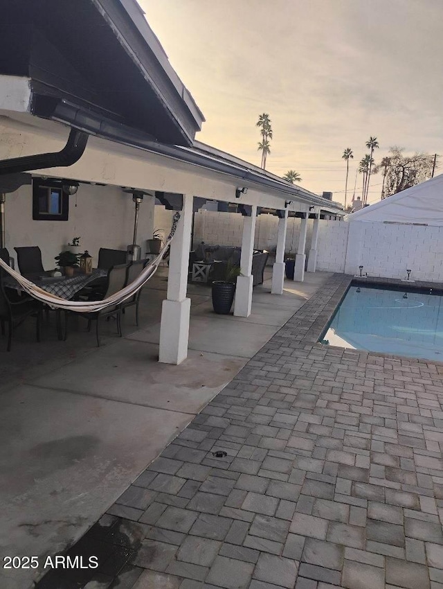 pool at dusk featuring a patio area