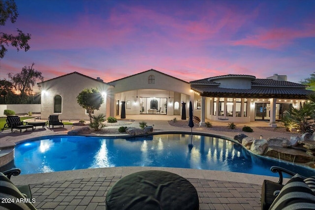 pool at dusk with a patio area