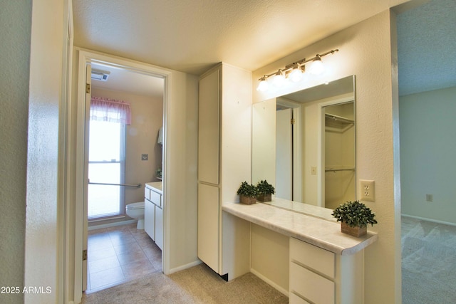 bathroom featuring vanity, toilet, visible vents, and a textured ceiling