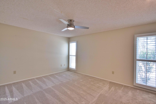 empty room with baseboards, light colored carpet, a textured ceiling, and ceiling fan