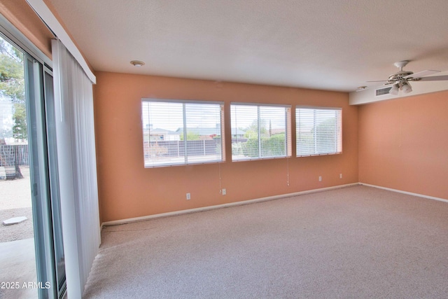 empty room featuring visible vents, plenty of natural light, light colored carpet, and ceiling fan