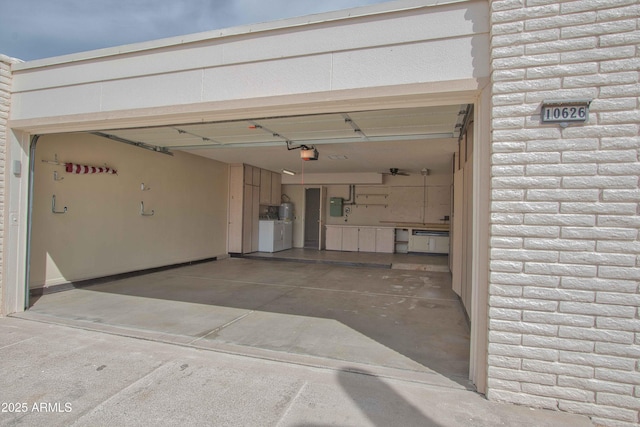 garage with washing machine and clothes dryer, concrete driveway, a garage door opener, and electric panel