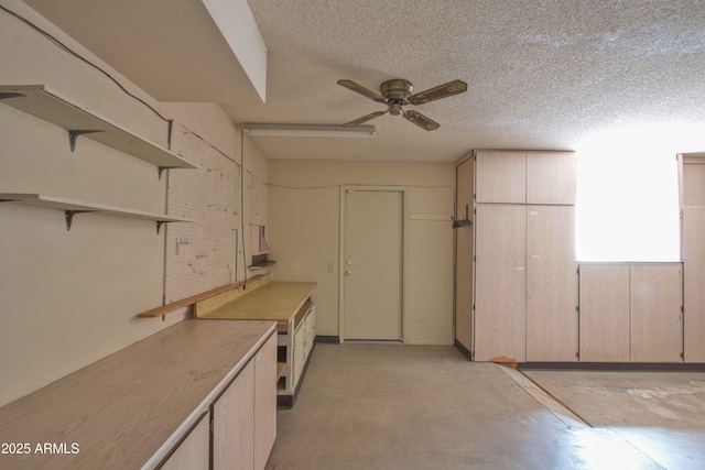 kitchen with a ceiling fan, open shelves, a textured ceiling, concrete floors, and light countertops