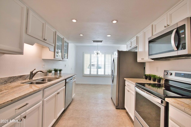 kitchen featuring light stone counters, appliances with stainless steel finishes, white cabinetry, and a sink