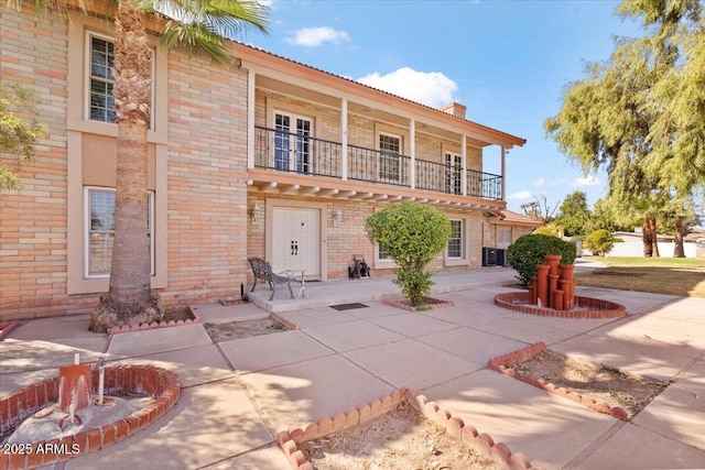 view of front of property featuring central AC unit, a patio area, and a balcony