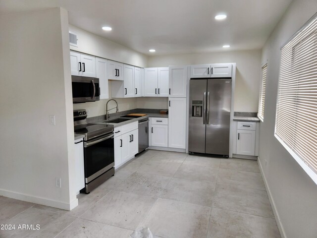 kitchen with sink, appliances with stainless steel finishes, white cabinets, and light tile patterned floors