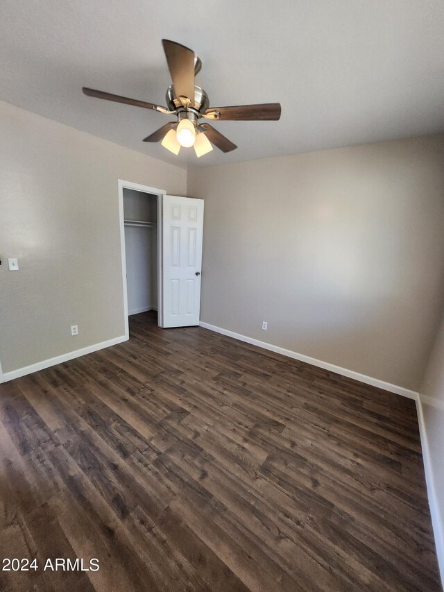 unfurnished bedroom with dark wood-type flooring, a closet, and ceiling fan