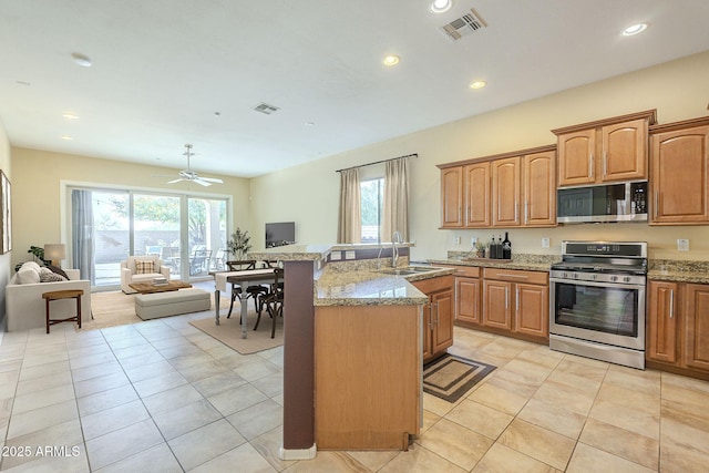 kitchen featuring light stone countertops, sink, an island with sink, stainless steel appliances, and a healthy amount of sunlight