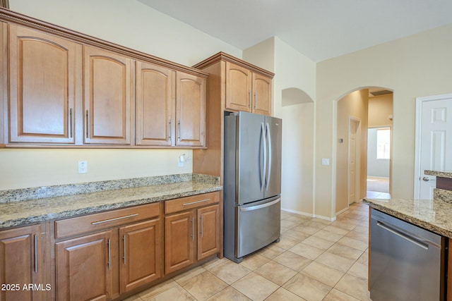 kitchen featuring light tile patterned floors, light stone countertops, and stainless steel appliances