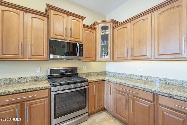 kitchen with light stone countertops, light tile patterned floors, and stainless steel appliances