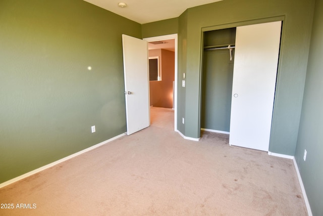 unfurnished bedroom with light colored carpet and a closet