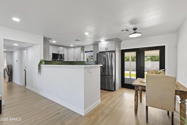 6723 E 1st Ave, Scottsdale, AZ 85251 - kitchen featuring stainless steel appliances, french doors, light wood-type flooring, tasteful backsplash, and a peninsula