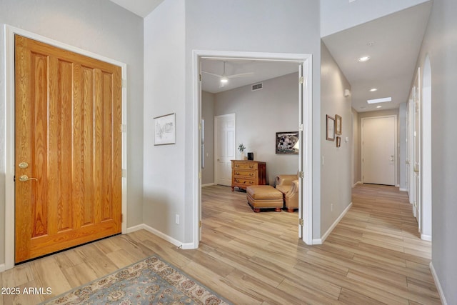 foyer with light wood finished floors, baseboards, and visible vents