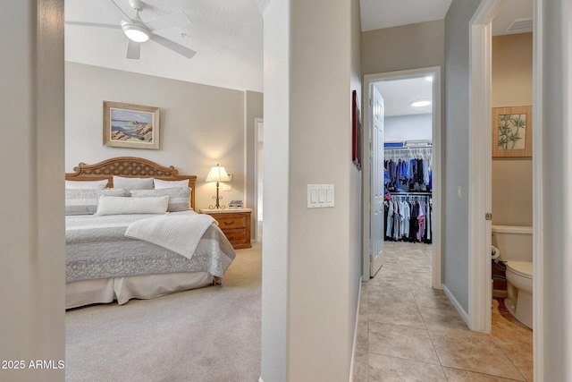 bedroom with a walk in closet, light tile patterned floors, a closet, visible vents, and light carpet