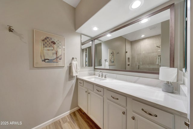 bathroom featuring recessed lighting, wood finished floors, vanity, baseboards, and a stall shower