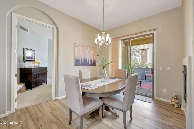 dining area featuring light wood-type flooring, visible vents, baseboards, and an inviting chandelier