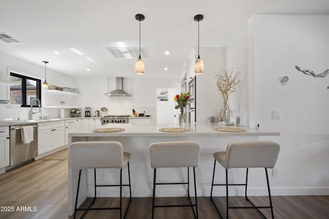 kitchen with dishwasher, backsplash, wood-type flooring, white cabinets, and wall chimney exhaust hood