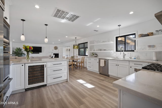 kitchen with tasteful backsplash, white cabinetry, sink, wine cooler, and stainless steel appliances