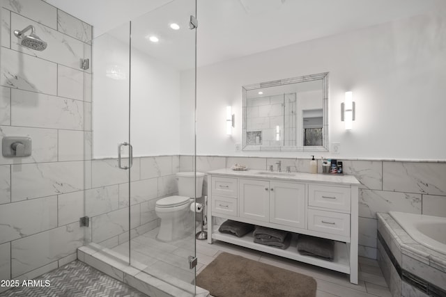 bathroom featuring toilet, a shower with shower door, tile walls, vanity, and tile patterned flooring