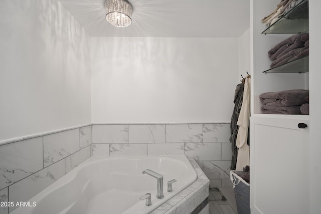 bathroom featuring tiled bath and an inviting chandelier