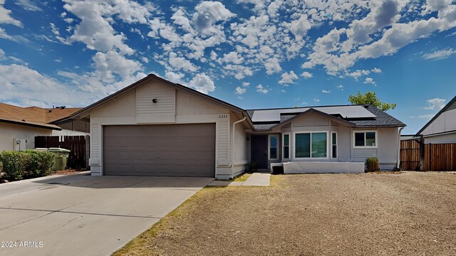 ranch-style house with solar panels and a garage