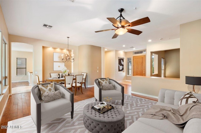 living room with ceiling fan with notable chandelier and light hardwood / wood-style flooring