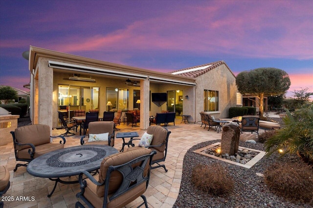 patio terrace at dusk featuring ceiling fan and a fire pit