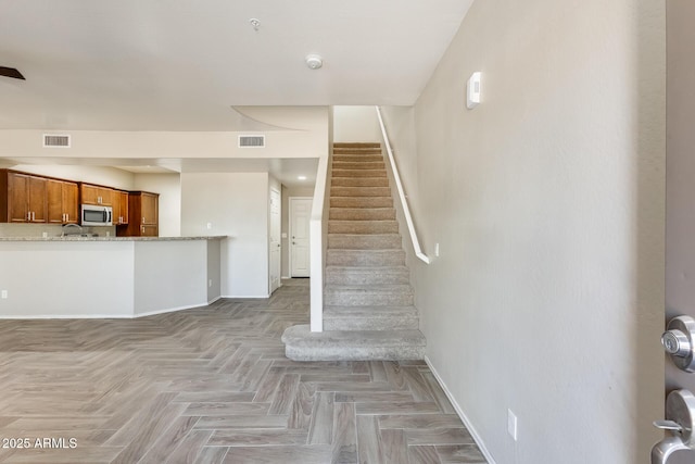 stairway featuring parquet flooring