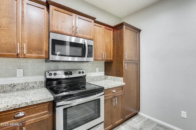 kitchen featuring light stone counters, stainless steel appliances, and tasteful backsplash