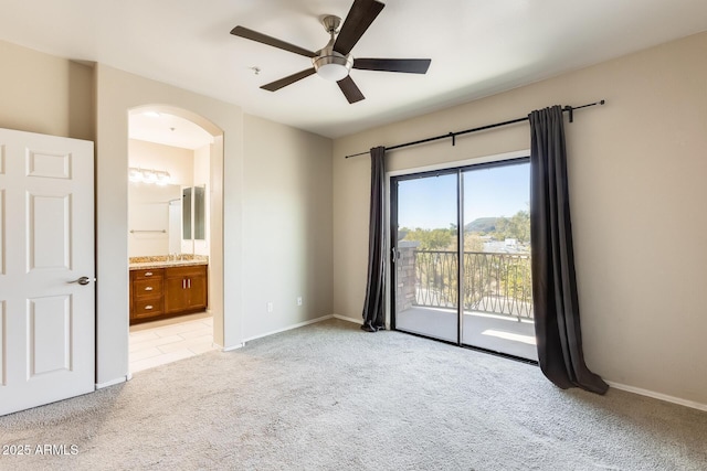 unfurnished bedroom featuring ensuite bathroom, ceiling fan, light colored carpet, and access to outside