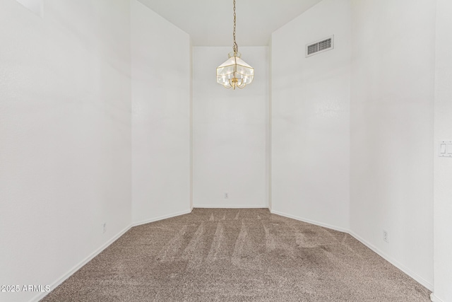 carpeted empty room featuring an inviting chandelier