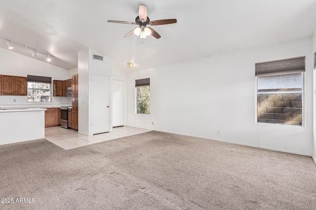 unfurnished living room featuring ceiling fan, lofted ceiling, rail lighting, and light carpet