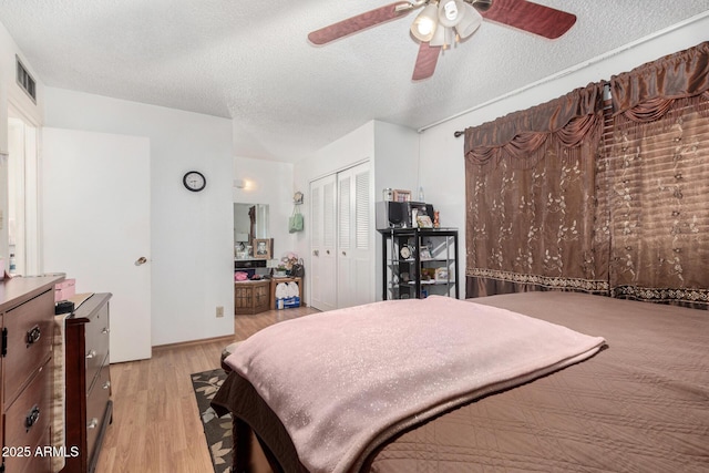 bedroom with light wood-type flooring, a textured ceiling, ceiling fan, and a closet