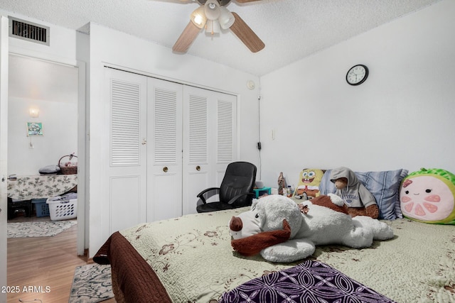 bedroom featuring a textured ceiling, a closet, hardwood / wood-style floors, lofted ceiling, and ceiling fan