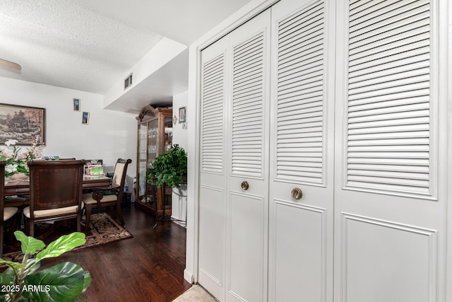 corridor featuring a textured ceiling and dark hardwood / wood-style flooring