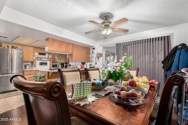 dining space with light tile patterned flooring, a textured ceiling, and ceiling fan