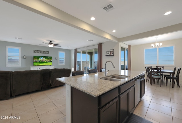 kitchen featuring a center island with sink, ceiling fan with notable chandelier, sink, light stone countertops, and light tile patterned flooring