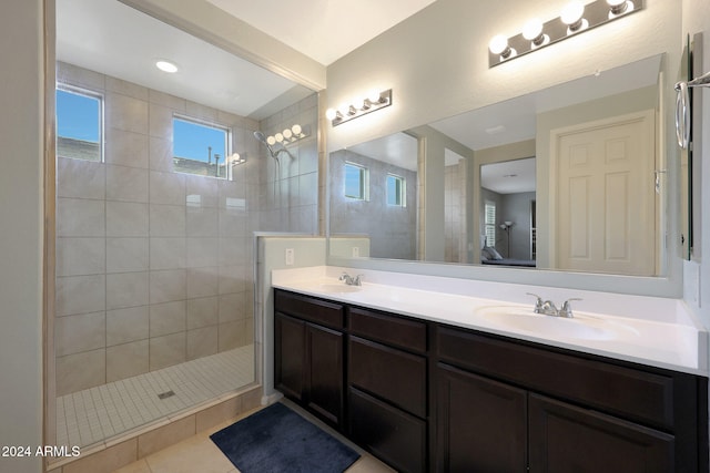 bathroom with tile patterned flooring, vanity, and a tile shower