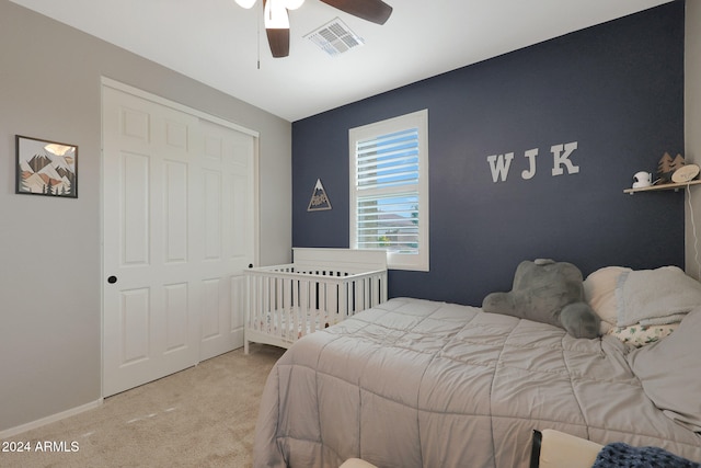 bedroom with ceiling fan, light carpet, and a closet