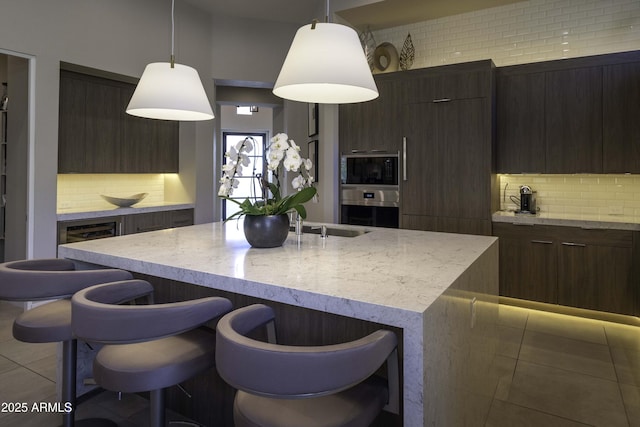 kitchen with hanging light fixtures, a kitchen island with sink, and decorative backsplash