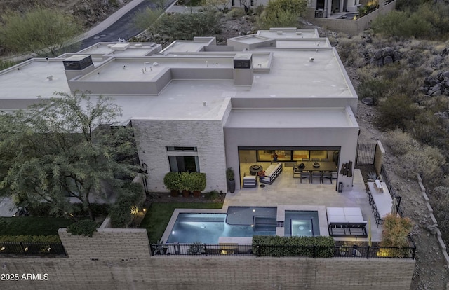 rear view of property with a patio area and an in ground hot tub