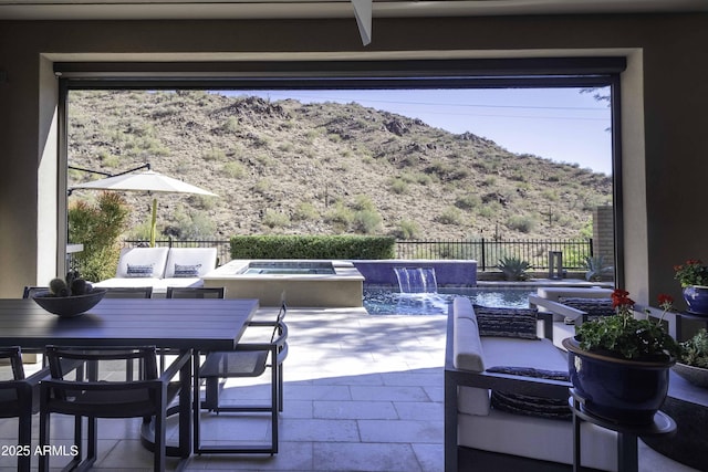 view of patio / terrace featuring pool water feature, a swimming pool with hot tub, and a mountain view