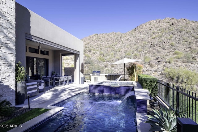 view of pool featuring exterior kitchen, a patio area, a mountain view, pool water feature, and an in ground hot tub