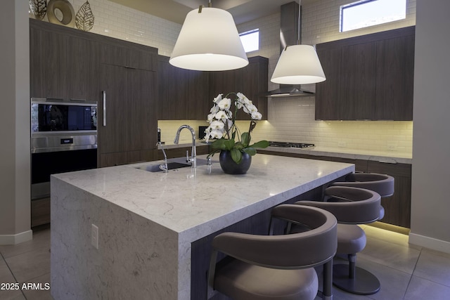 kitchen featuring sink, a center island with sink, light tile patterned floors, appliances with stainless steel finishes, and pendant lighting